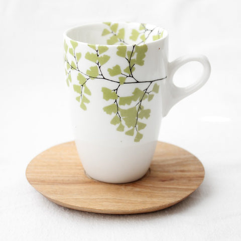 White coffee mug with fern print and wooden saucer 